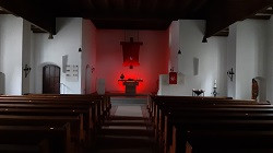 Pfingsten 2020: rotes Banner am Kreuz und stimmungsvolles Licht in der Apsis